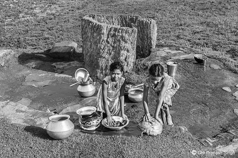 Young girls cleaning utensils near the Kukuru Daarhi in Jiuri village, Jharkhand, India